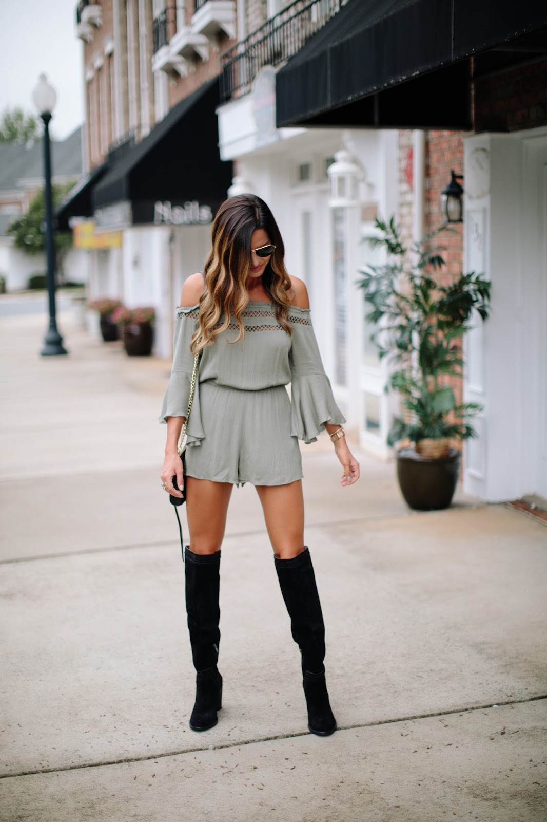 woman in green romper with black over the knee boots