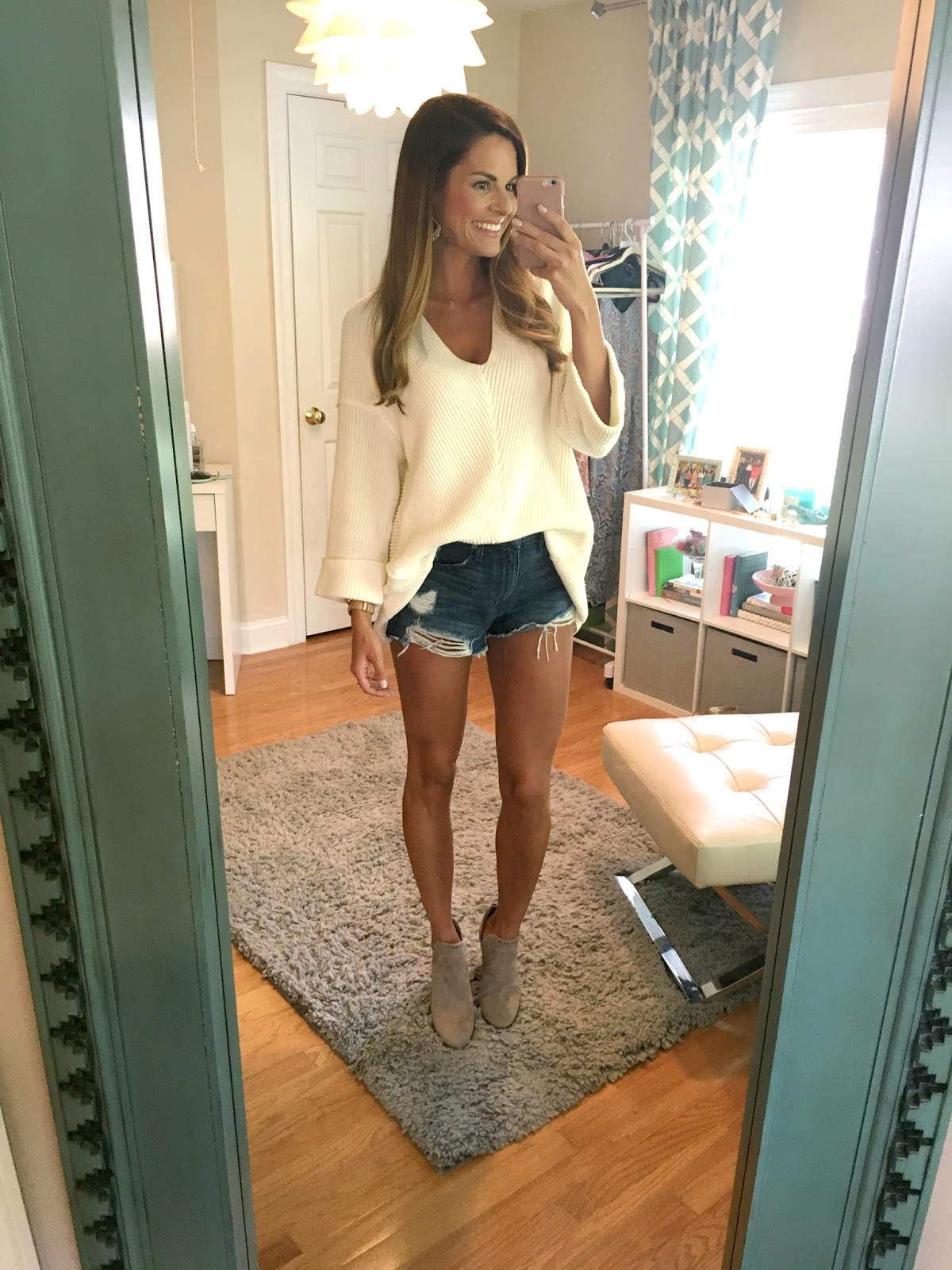 woman wearing oversized sweater with denim cutoff shorts with ankle boots