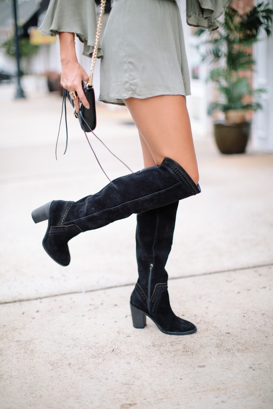 closeup of black over the knee boots with shorts romper