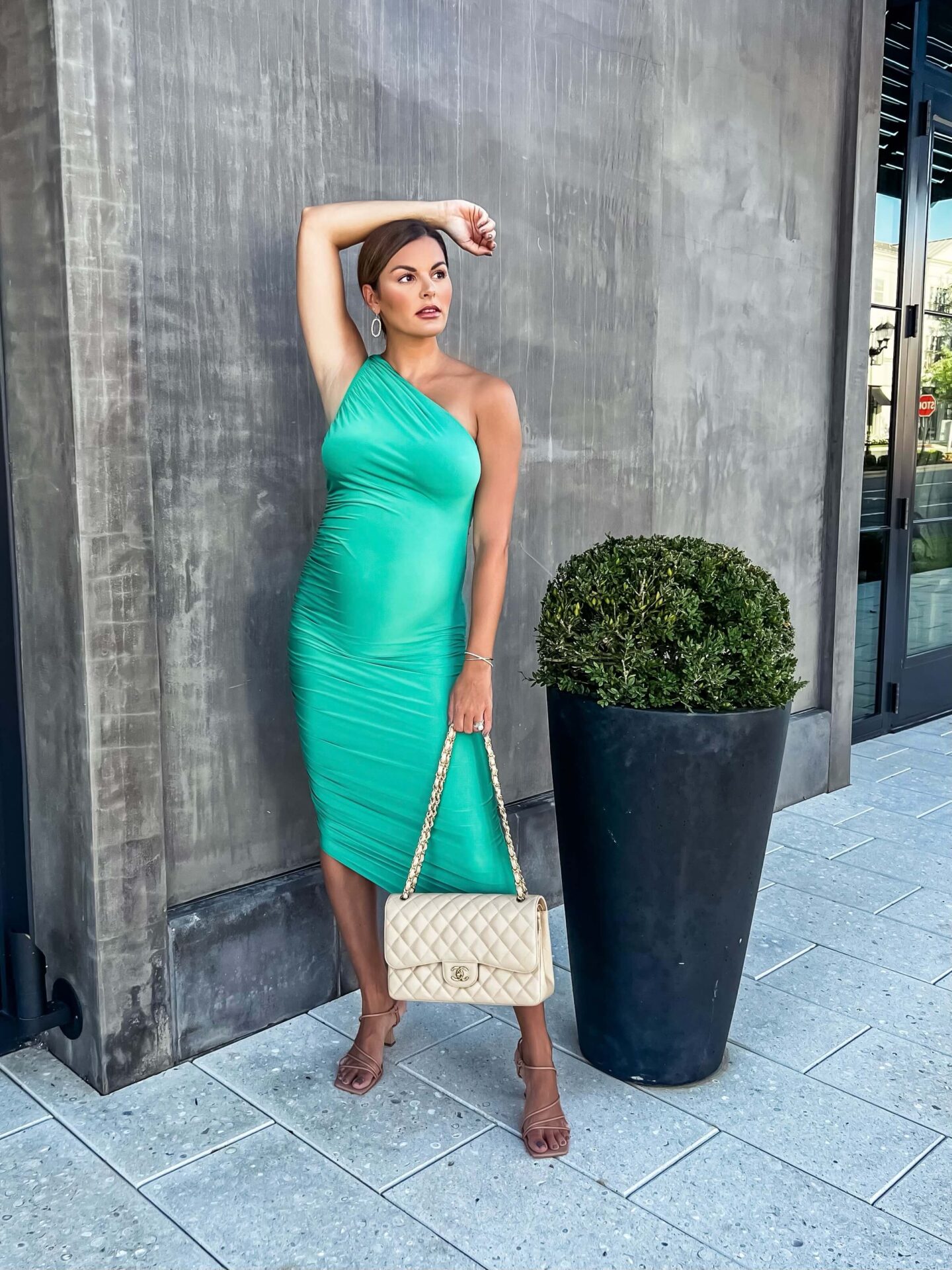 woman in green done shoulder dress in front of concrete wall