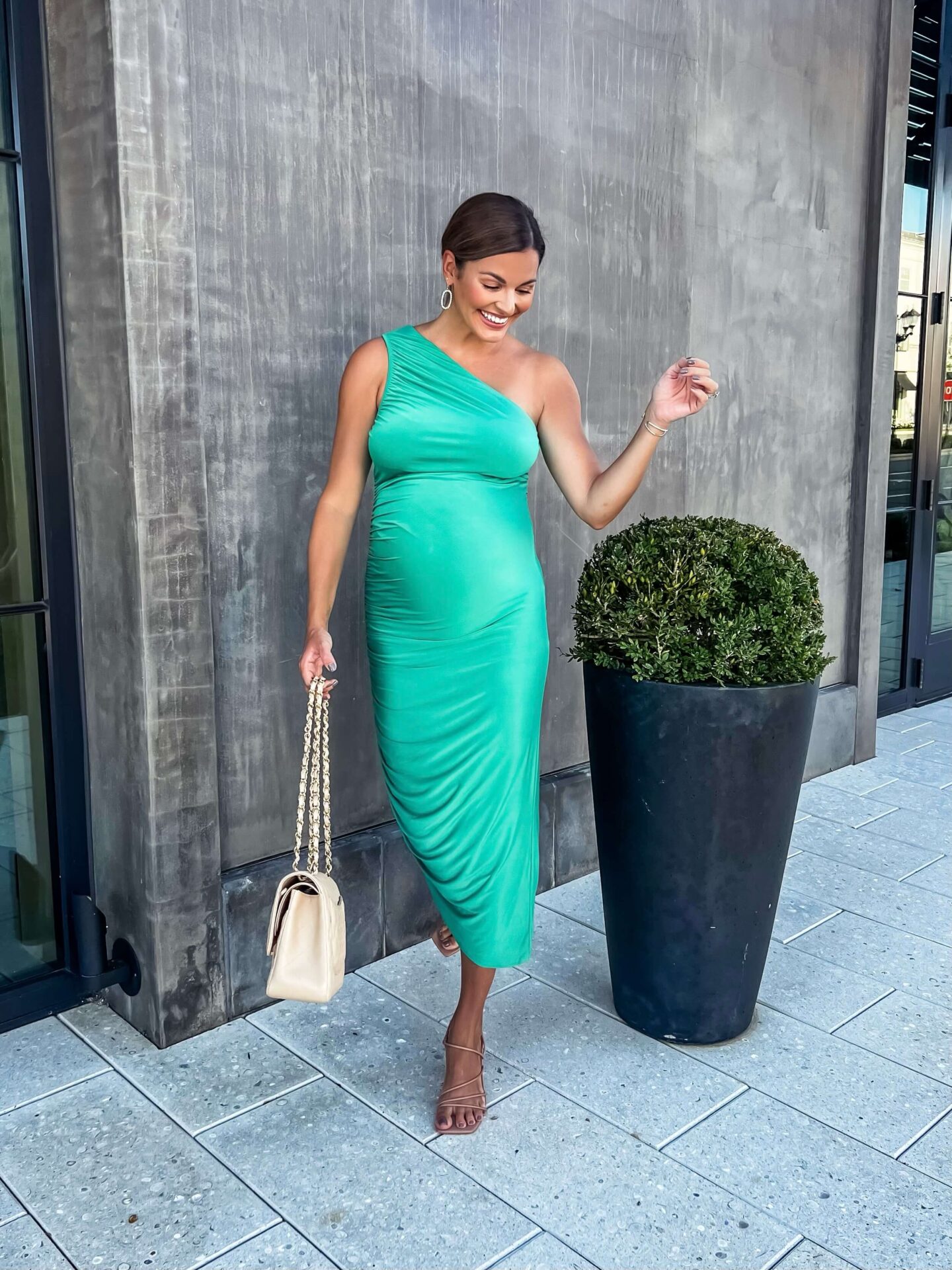 woman in green done shoulder dress in front of concrete wall