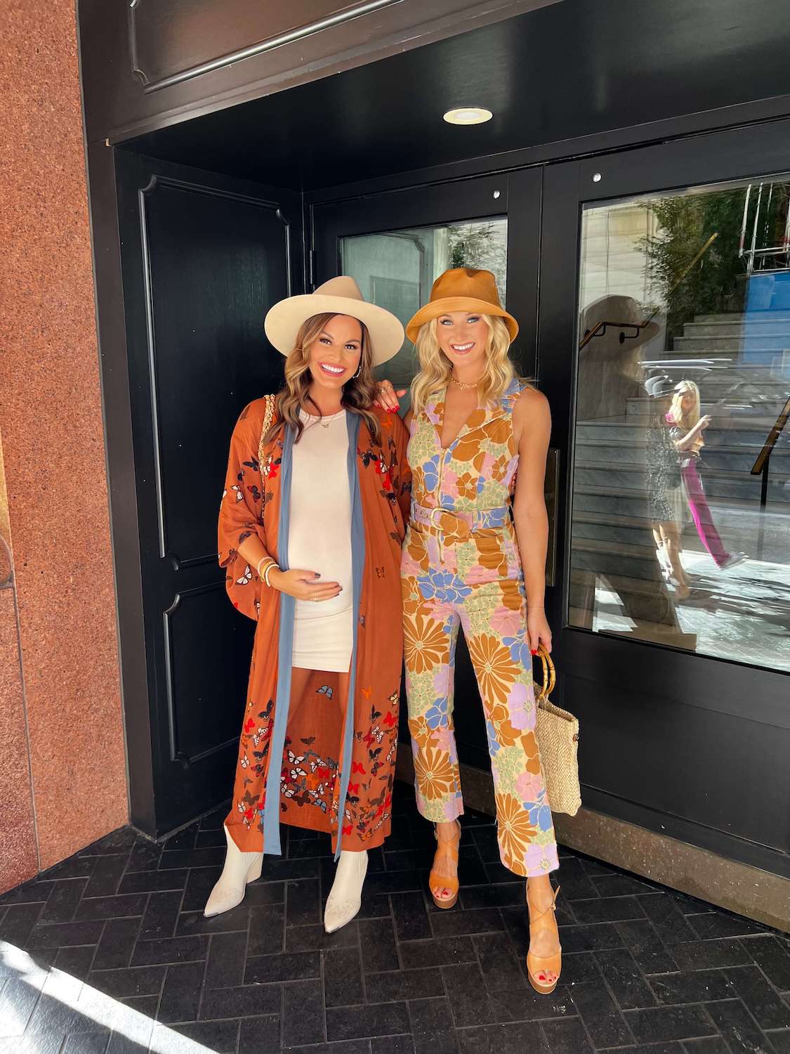 2 women dresed up in front of glass doors wearing hats