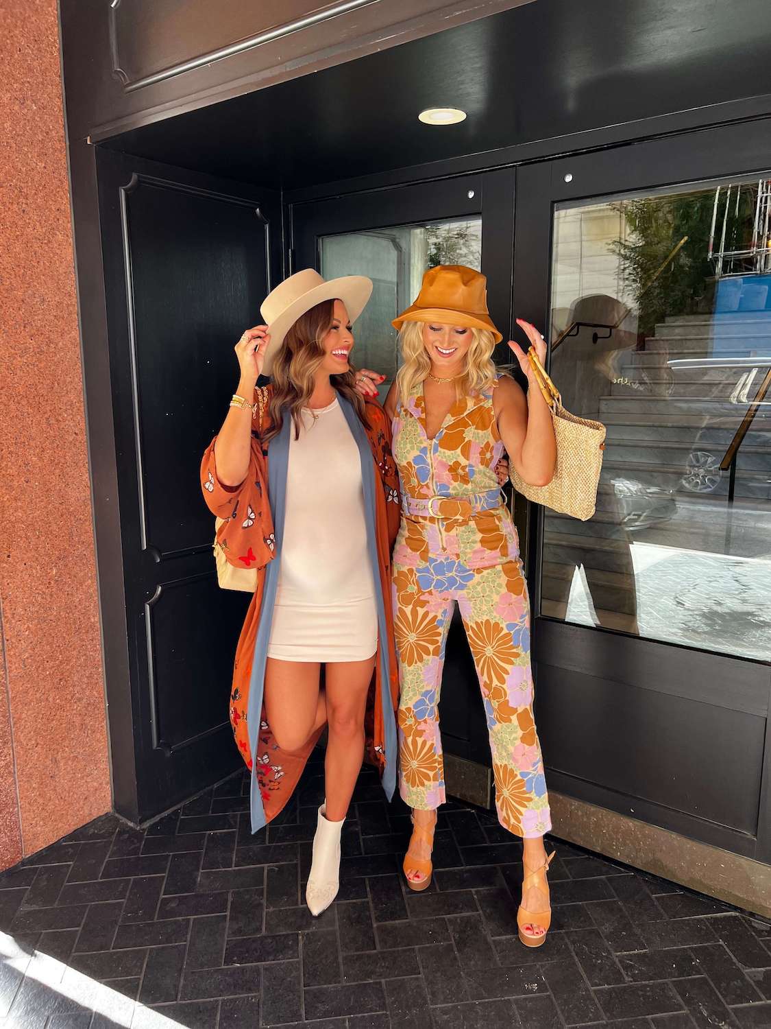 2 women dresed up in front of glass doors wearing hats