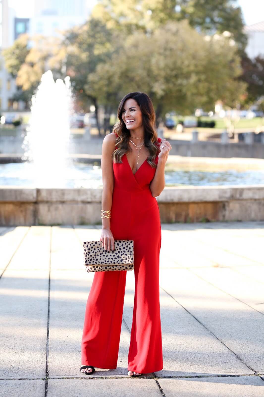 woman in red jumpsuit holding leopard clutch