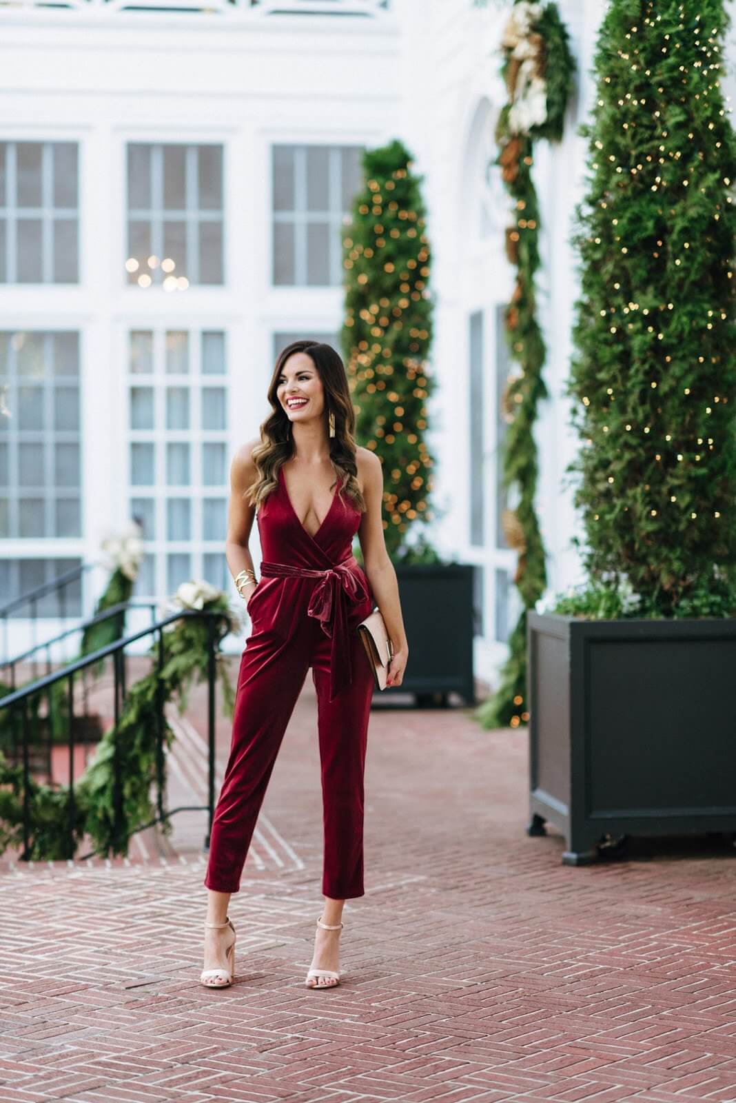 woman in red velvet jumpsuit in front of building with large windows