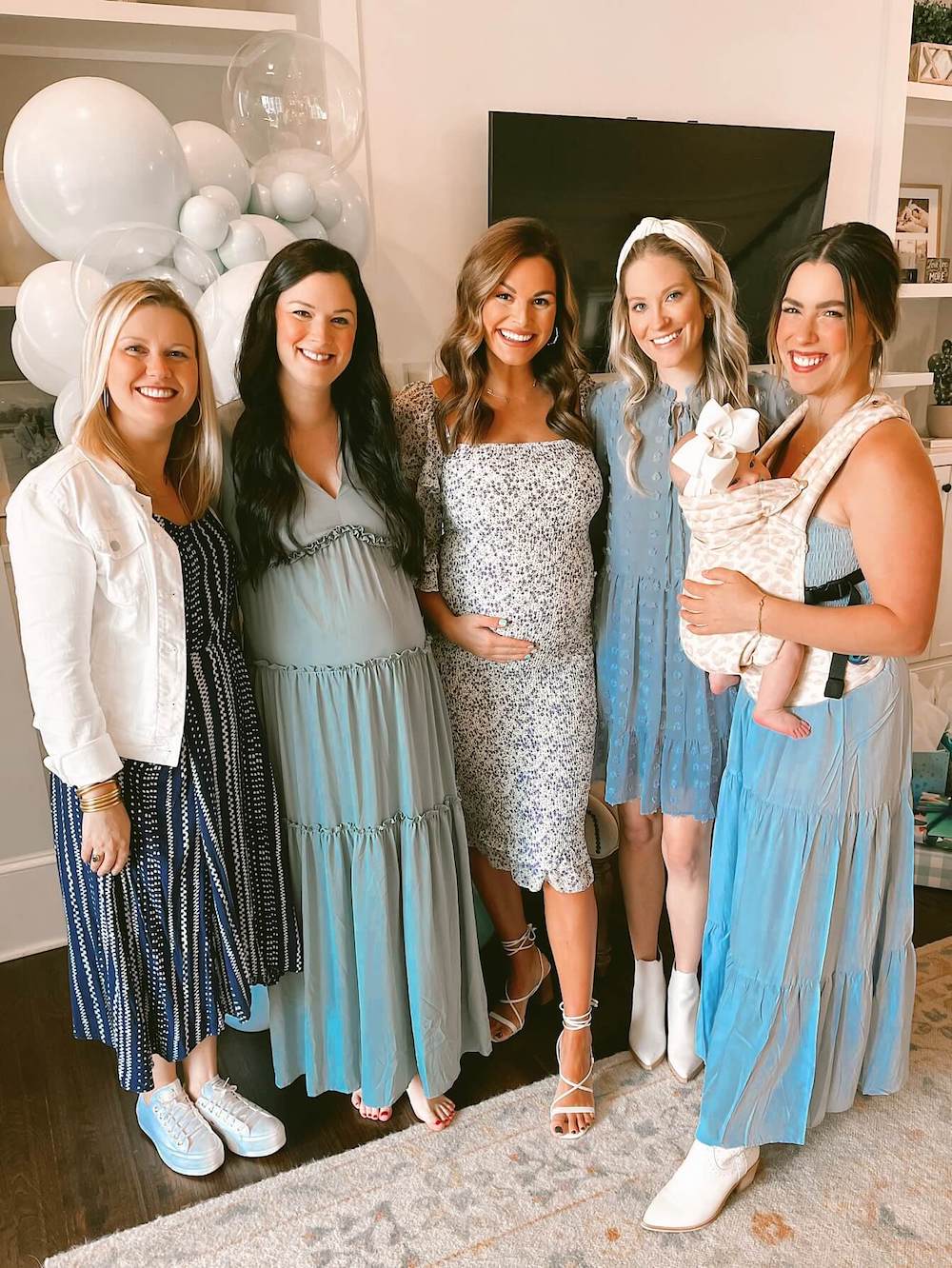 pregnant woman and friends standing in front of a fireplace
