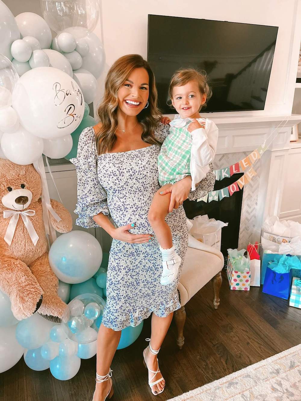 pregnant woman holding daughter in front of fireplace