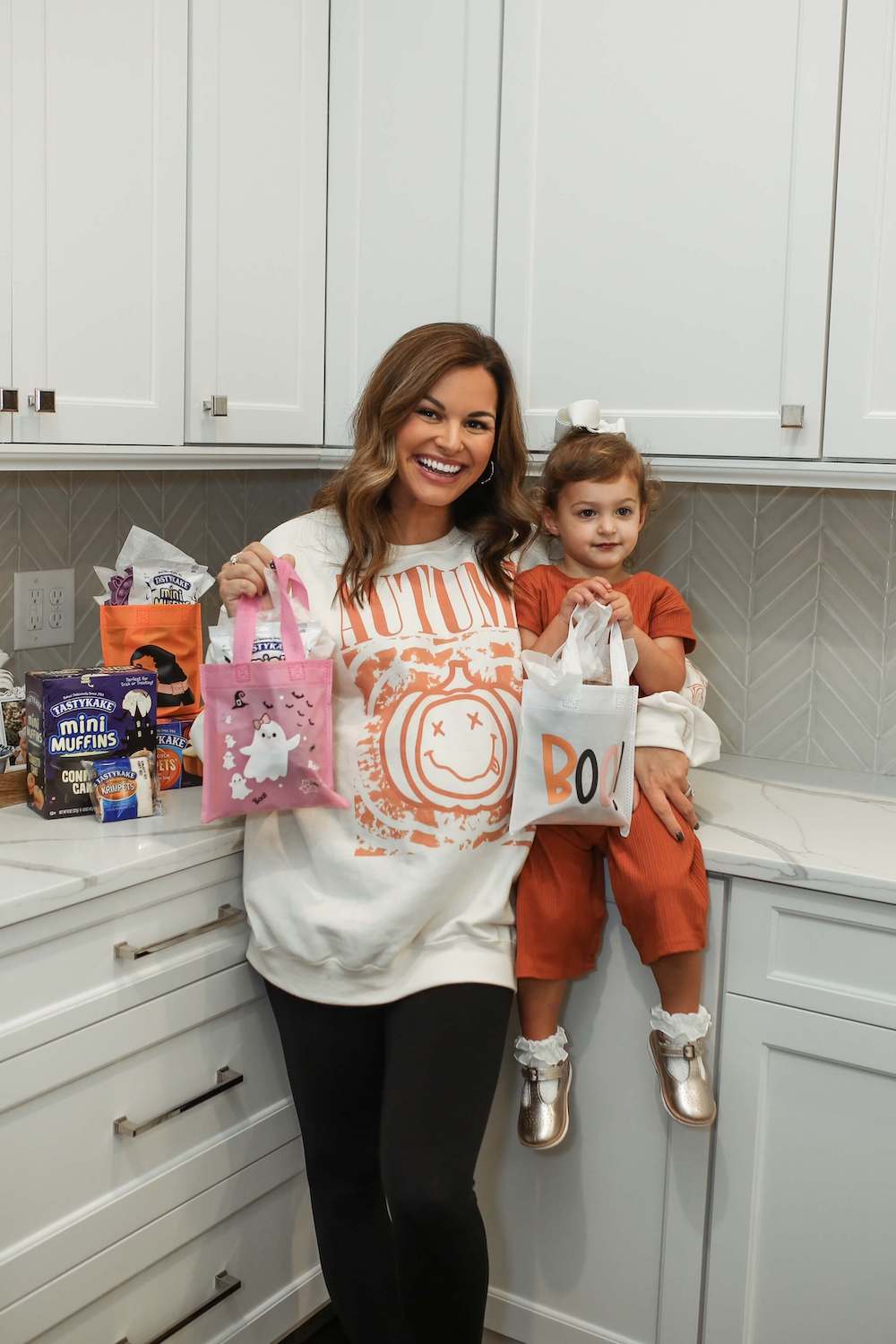 woman and little girl with brown hair holding boo bags