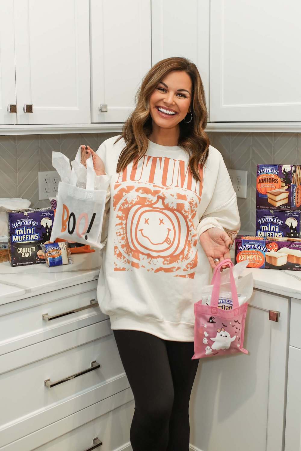 woman with autumn sweatshirt with tastykake things behind her