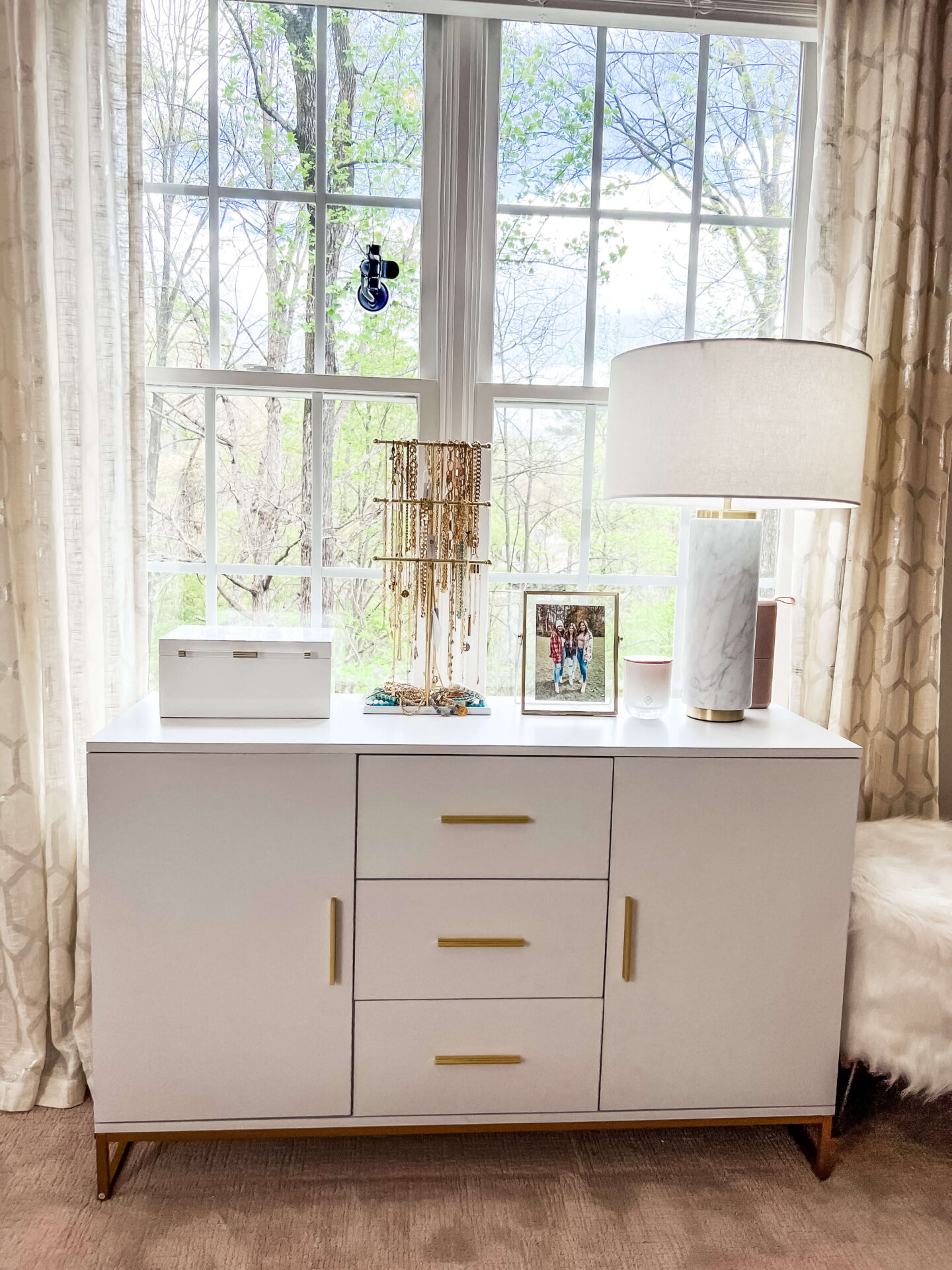 white sideboard under a window in a small room turned into a walk in closet