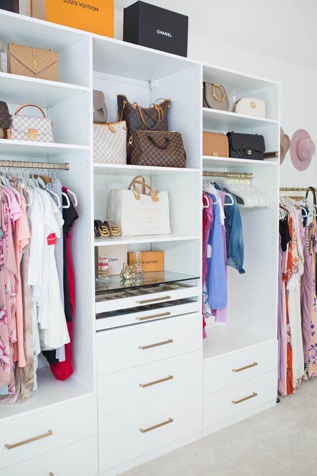 closet room with purses and clothes in white built in shelving units