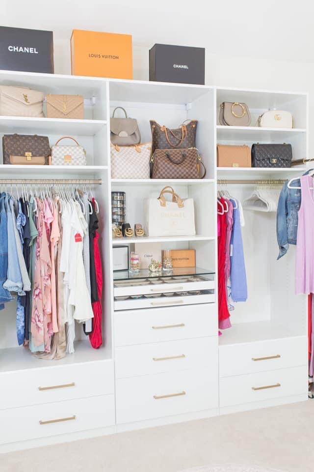 closet room with purses and clothes in white built in shelving units