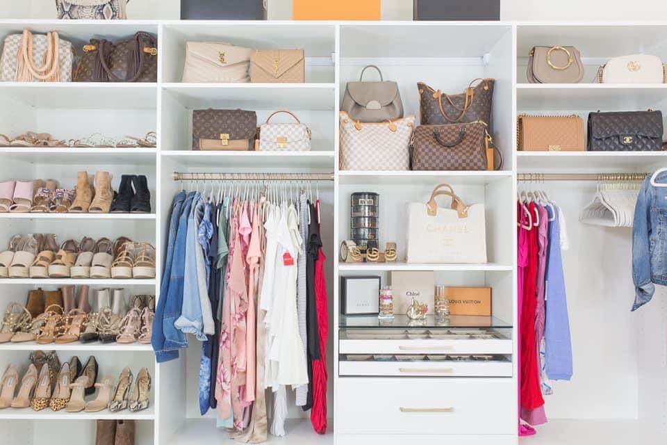 closet room with purses and clothes in white built in shelving units