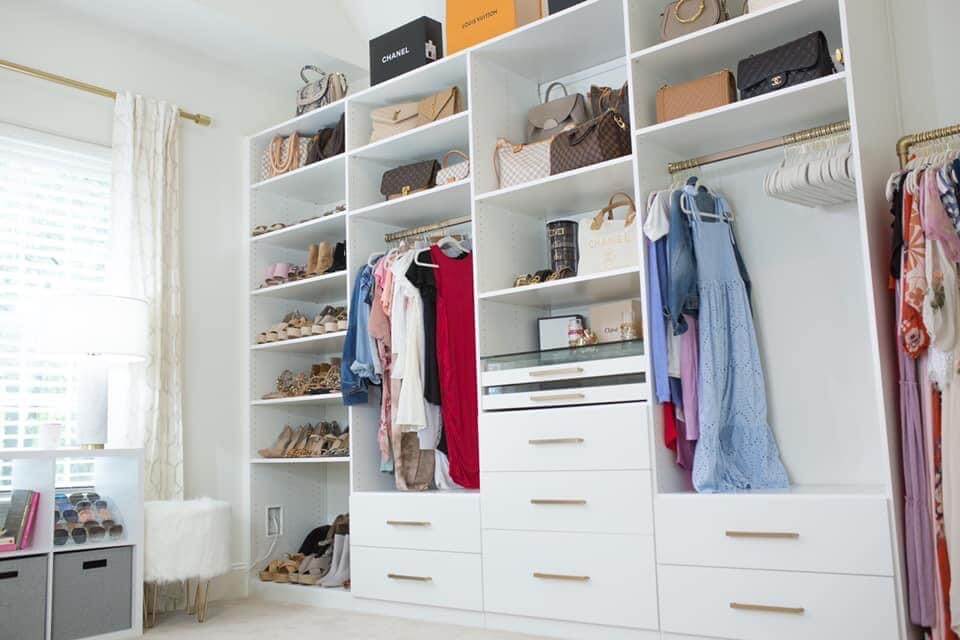 closet room with purses and clothes in white built in shelving units