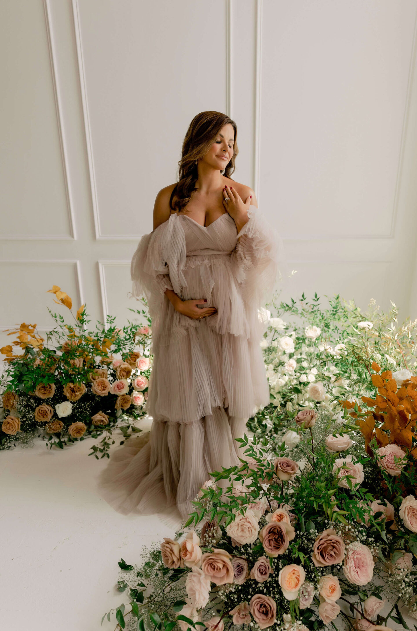 pregnant woman standing with flowers around her at maternity photoshoot