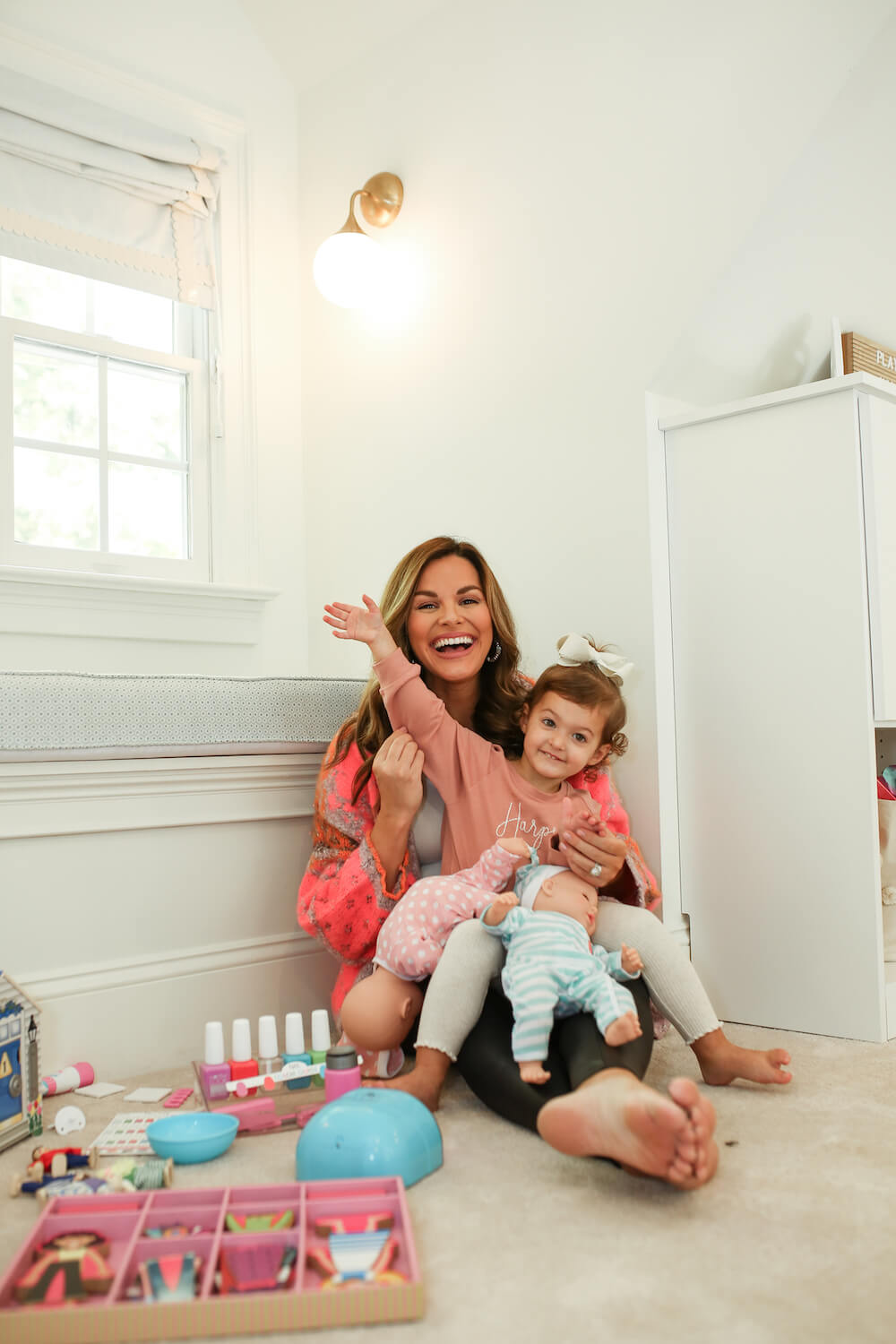 mom with little girl in her lap playing with melissa and doug toys for two year old on the floor