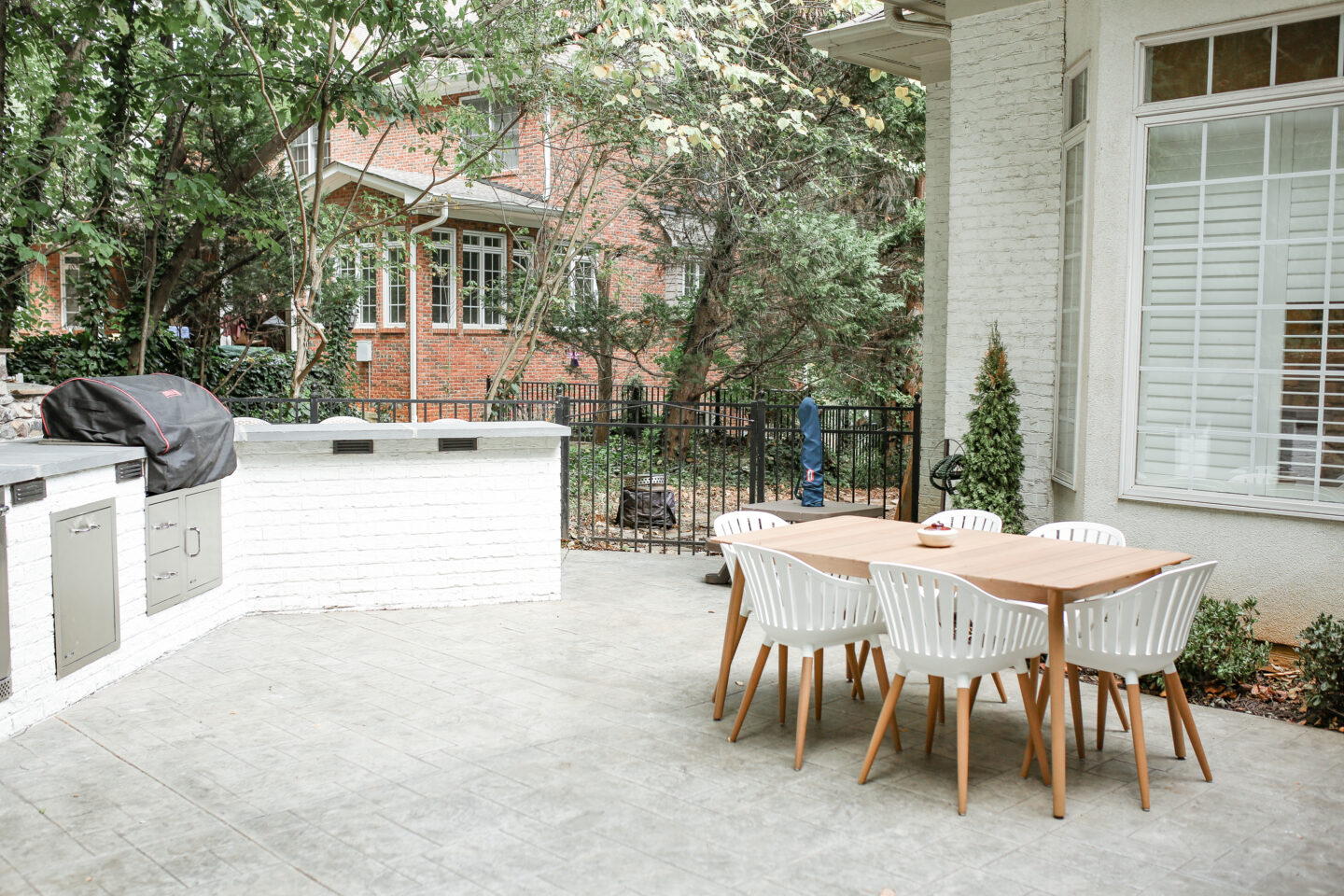 white outdoor kitchen and brown table with dining chairs