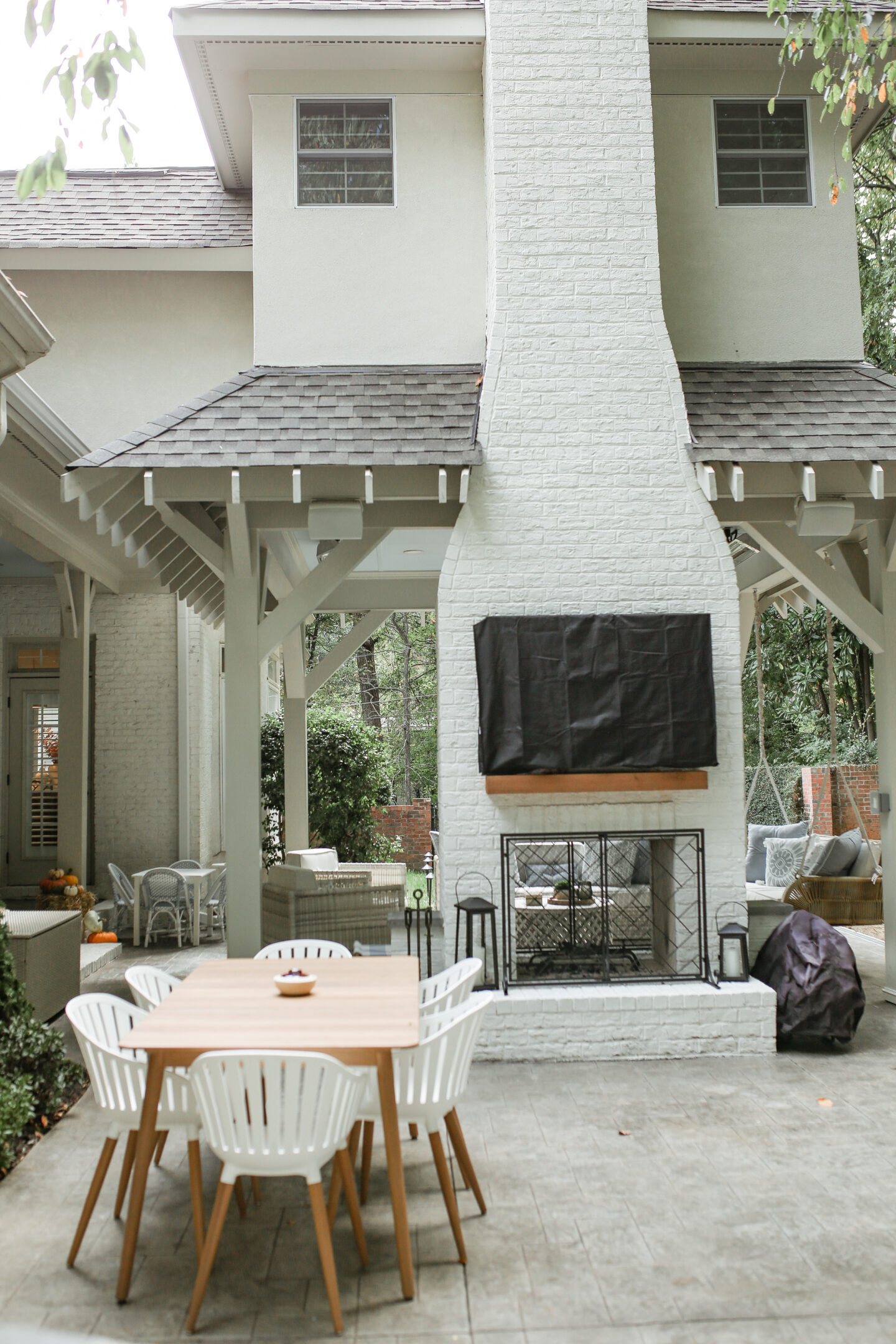 large outdoor brick fireplace with TV and outdoor table and chairs