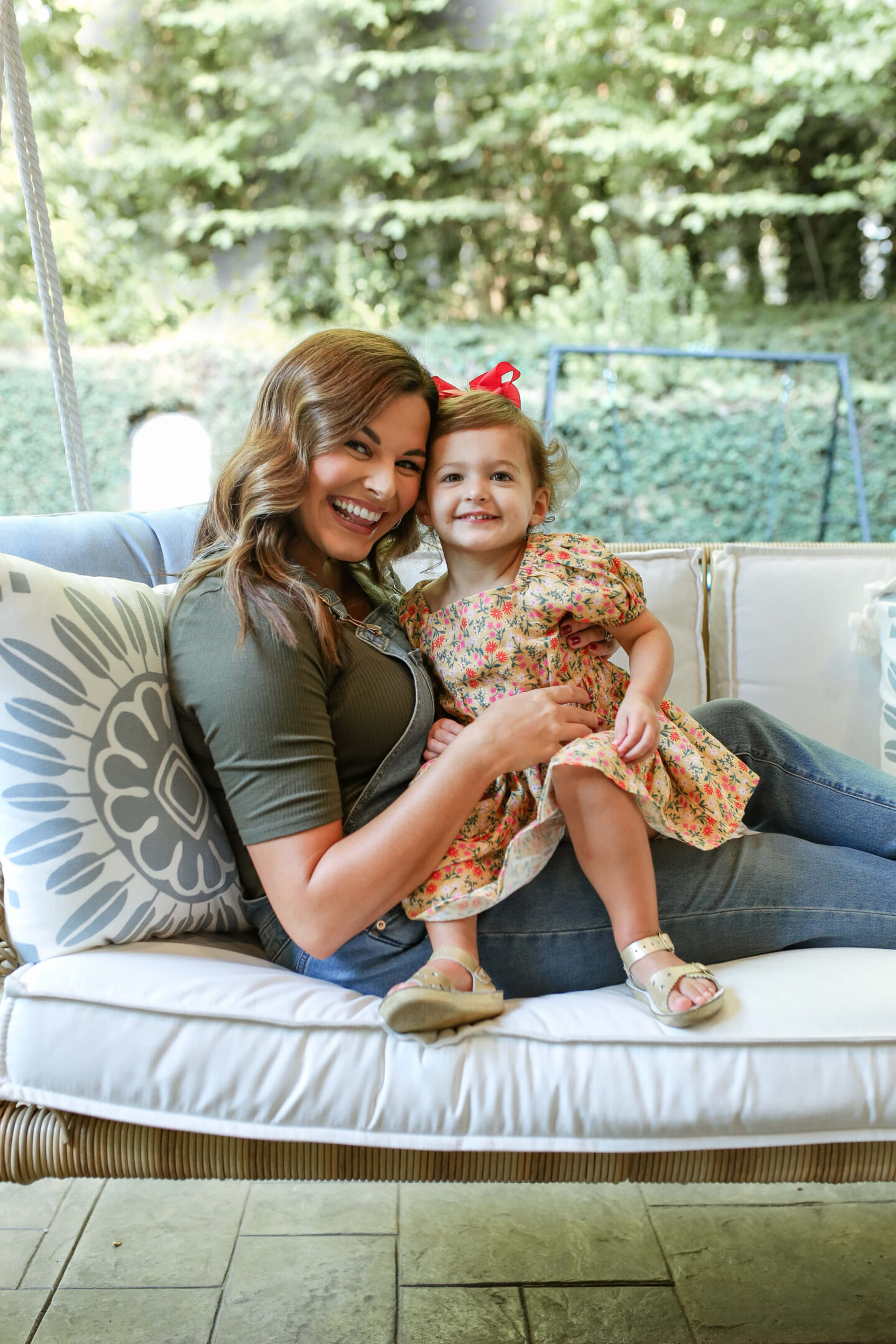 mom holding little girl on outdoor daybed on back patio