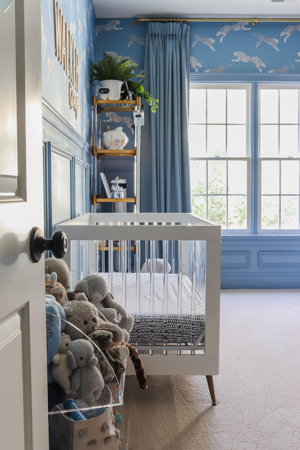white crib with acrylic bars and blue walls in a nursery