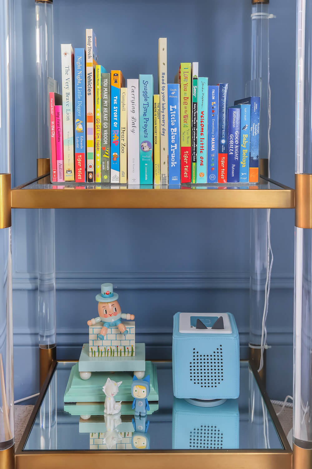 acrylic and gold shelves with baby board books and Tonies