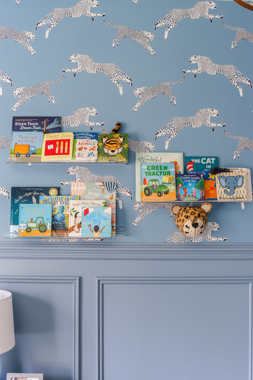 acrylic shelves with books in adventure themed nursery with leopard wallpaper
