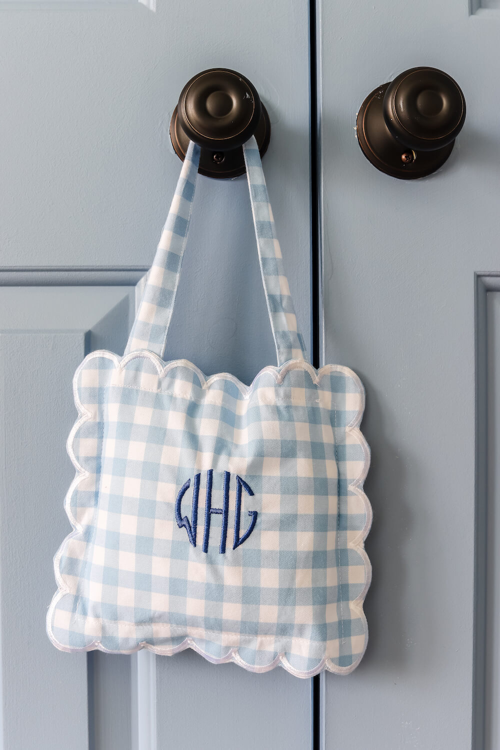 white and blue gingham pillow with WGH initials on it