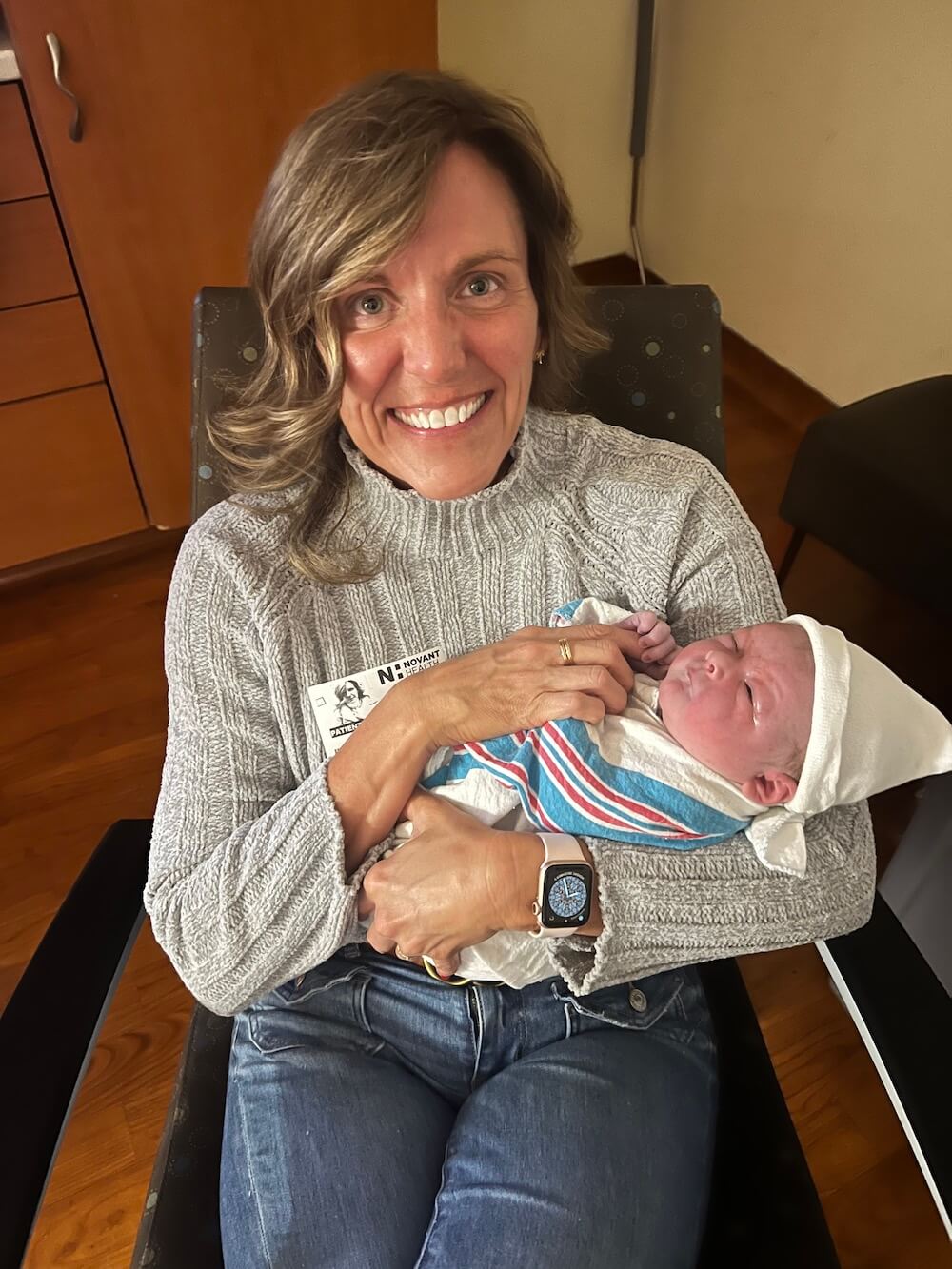 older woman holding newborn baby in hospital