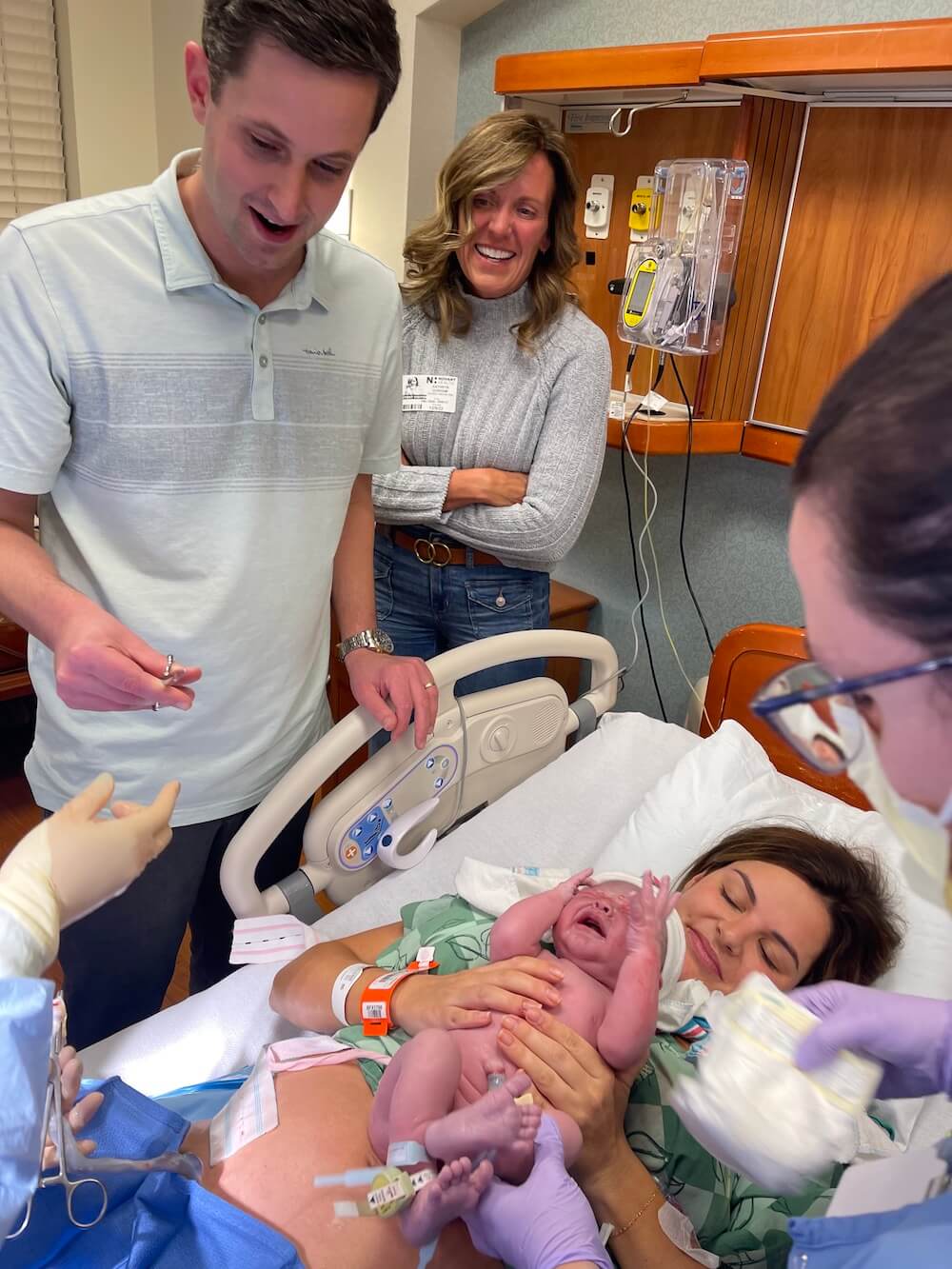 man and woman looking down at woman who just gave birth in hospital bed