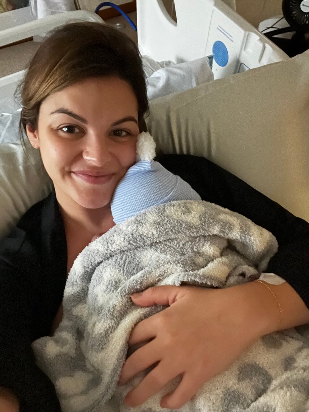 new mom in the hospital wearing black robe holding her new baby boy