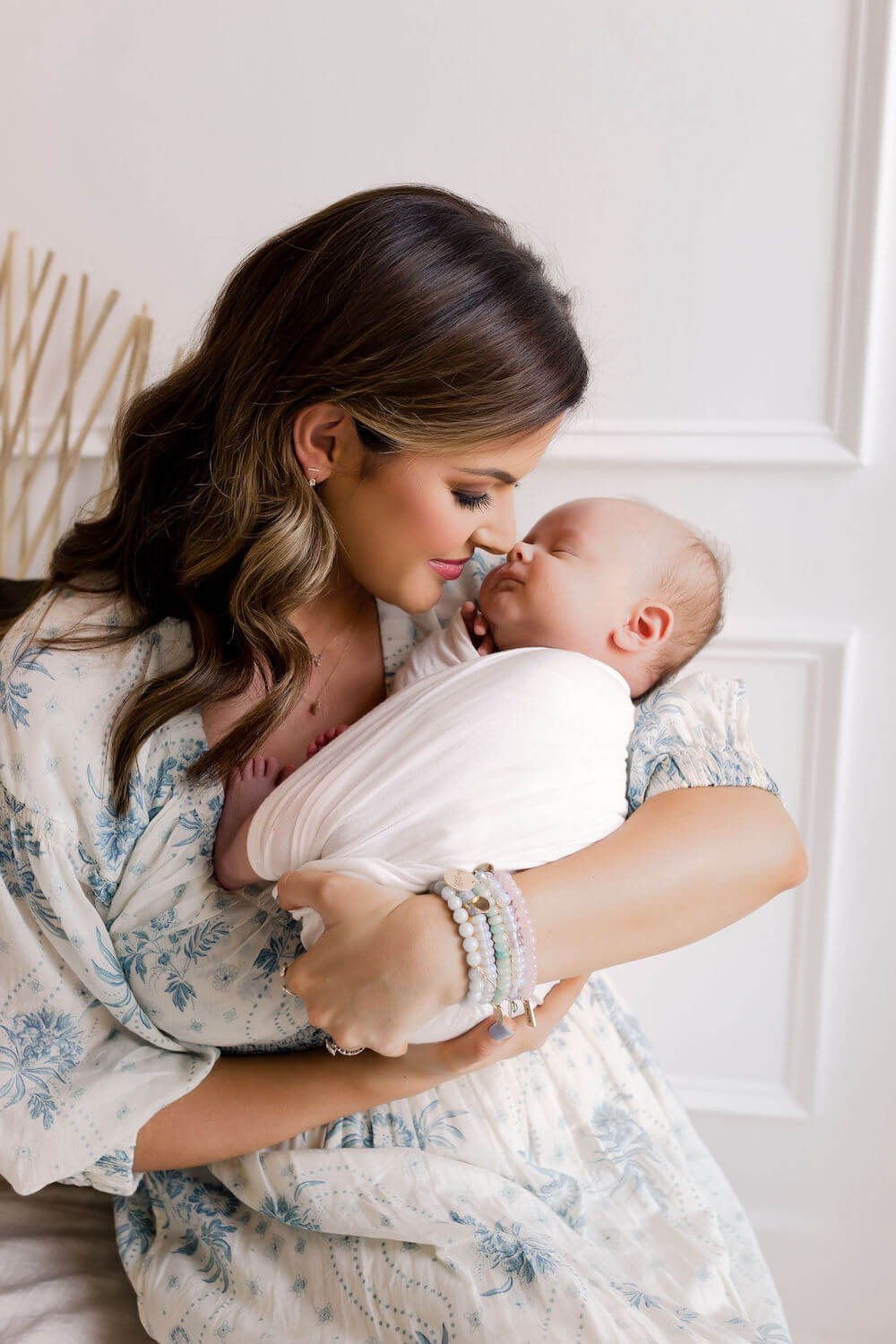 woman holding baby swaddled in white wrap