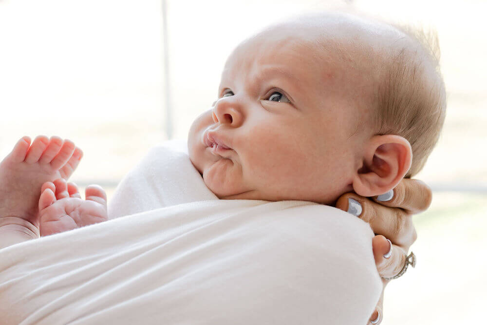 closeup of baby boy in white swaddle