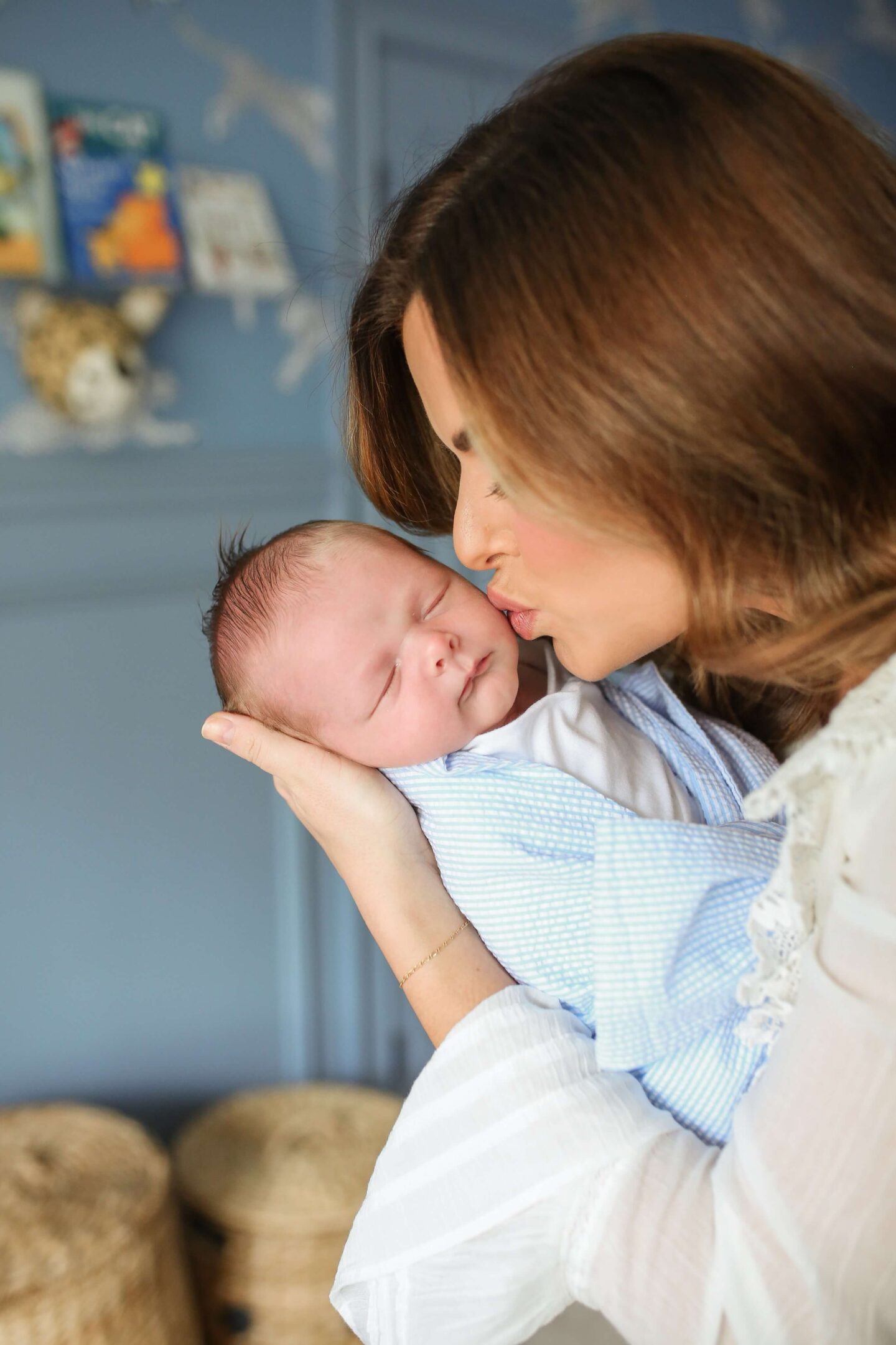 mom holding newborn baby giving him a kiss on the cheek 