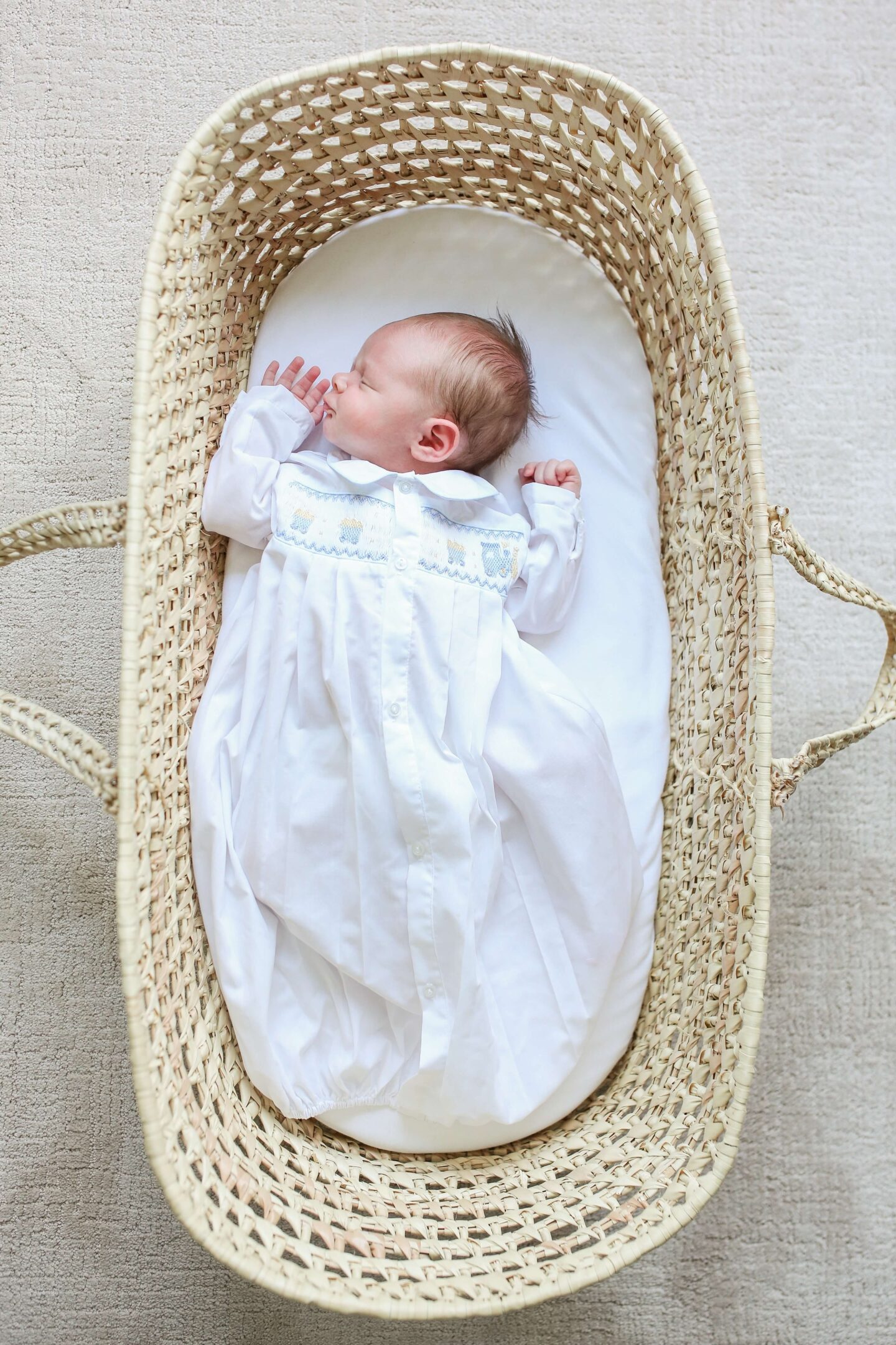 little boy laying in moses basket for newborn photoshoot at home