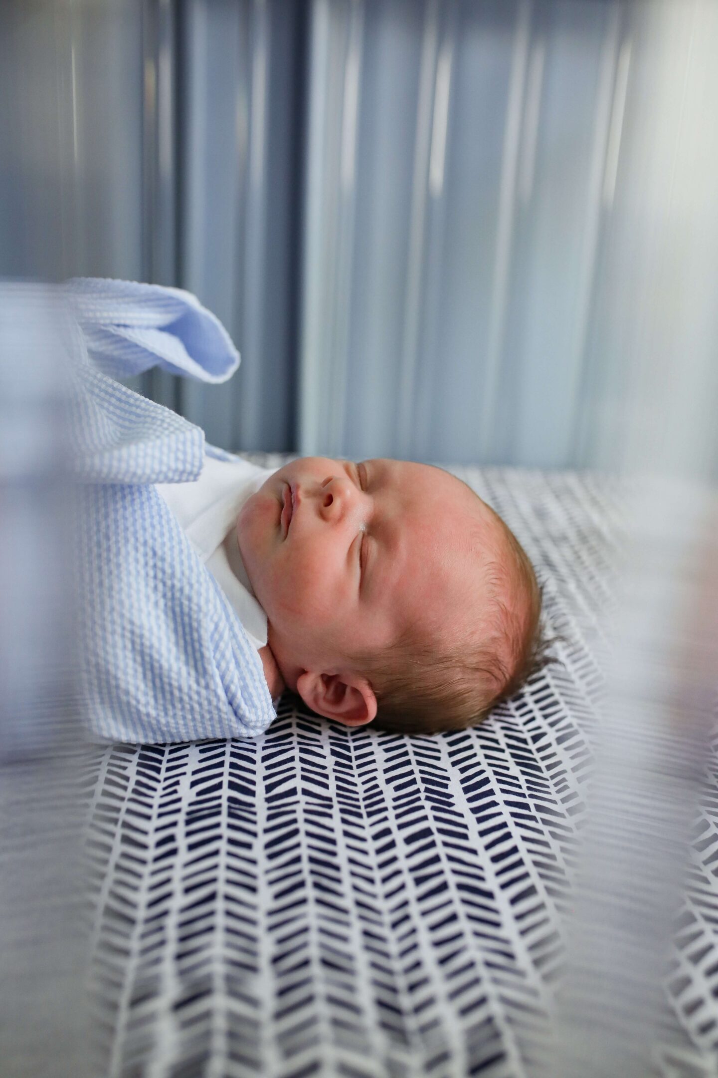 newborn baby boy laying in crib swaddled asleep