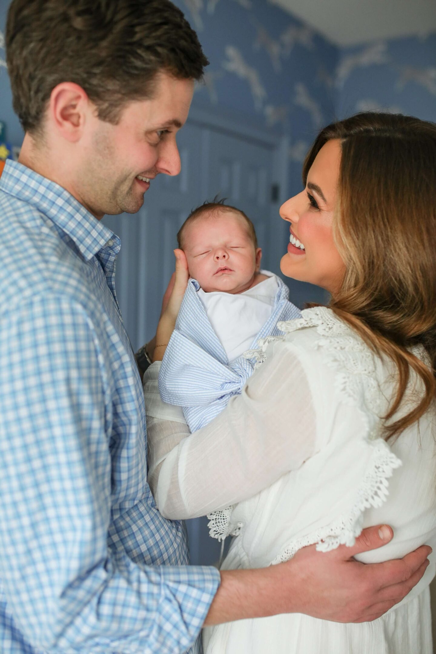 man and woman looking at one another smiling holding their newborn baby boy