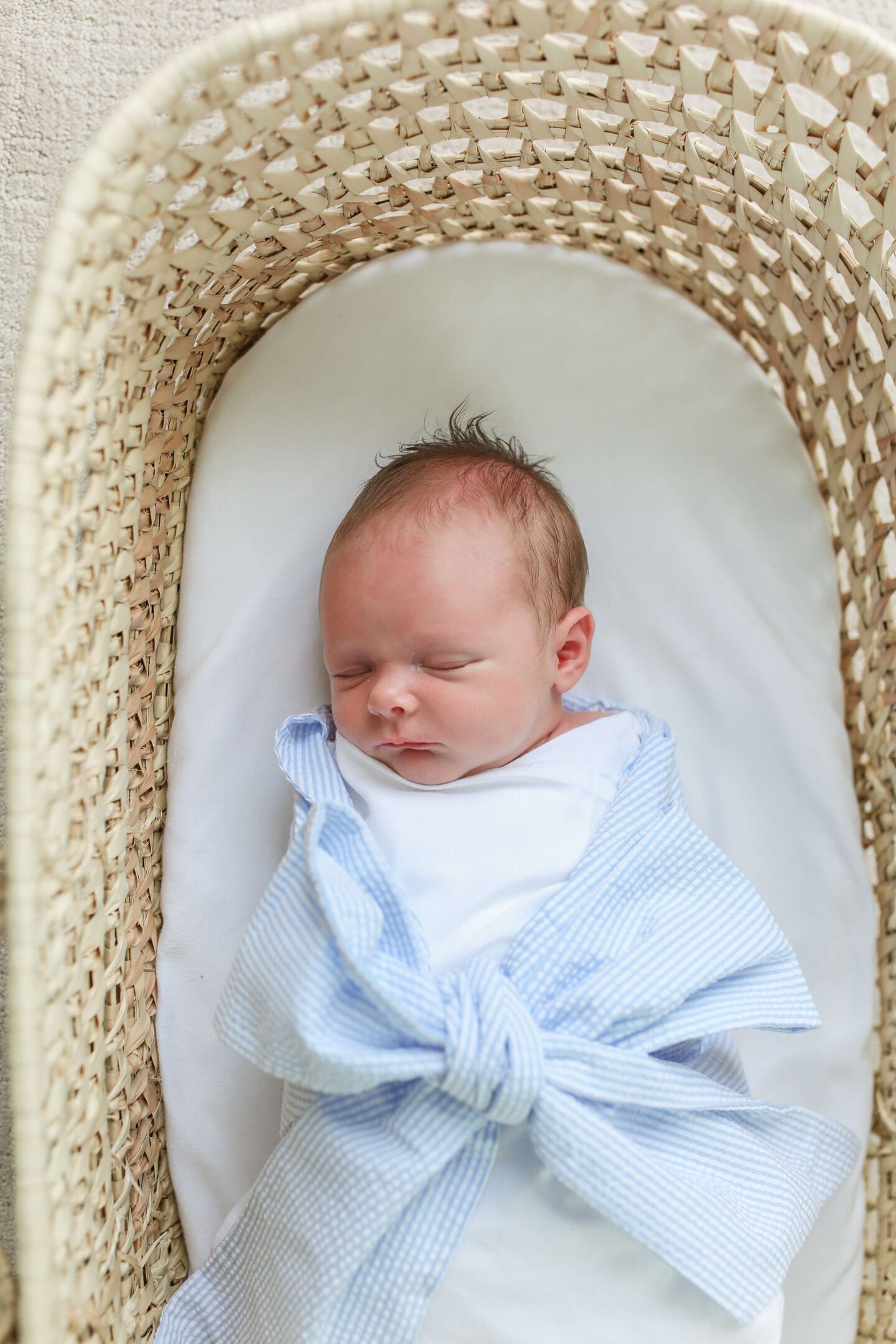 little boy in moses basket sleeping and wrapped in swaddle