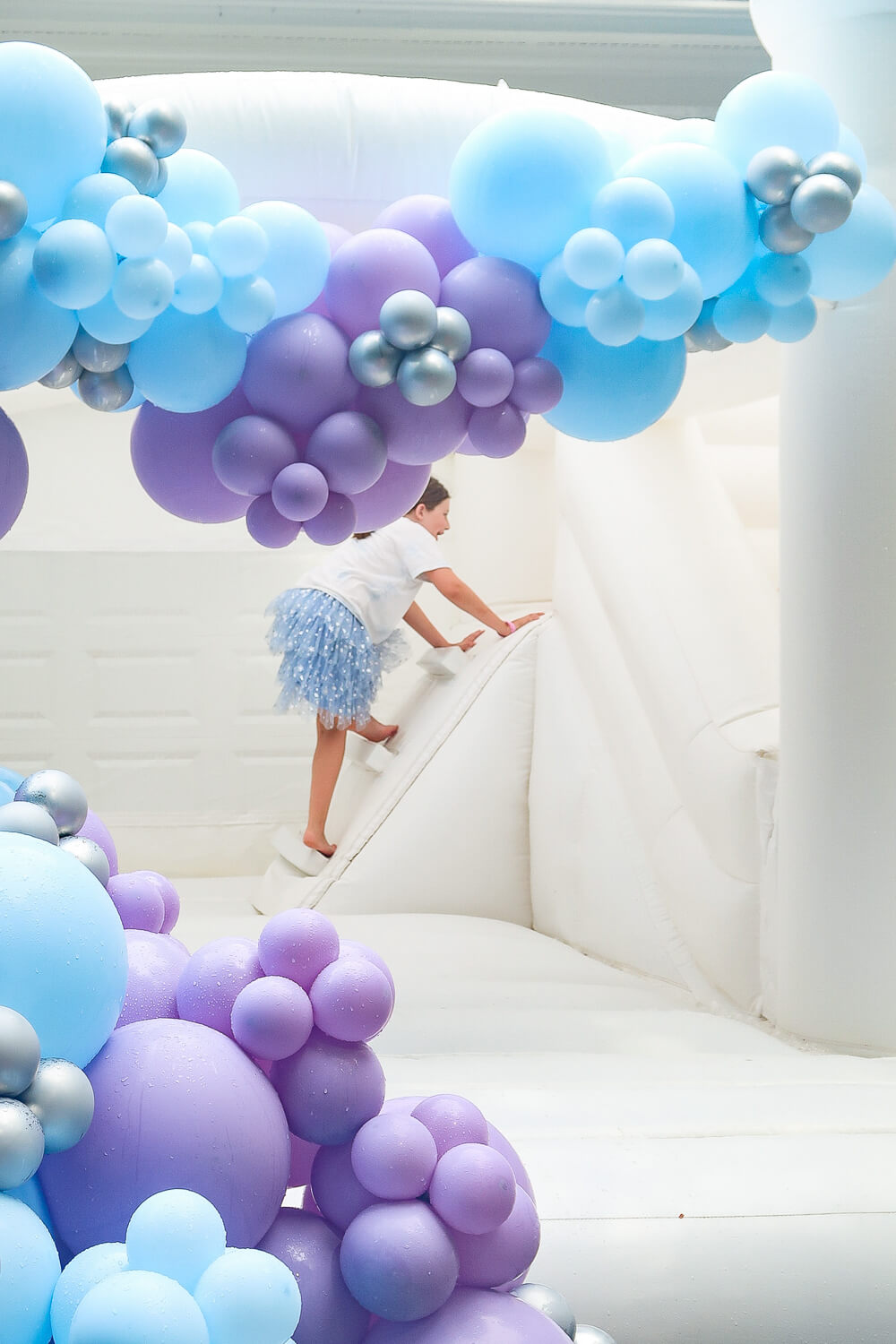 white bouncy castle with balloon arches