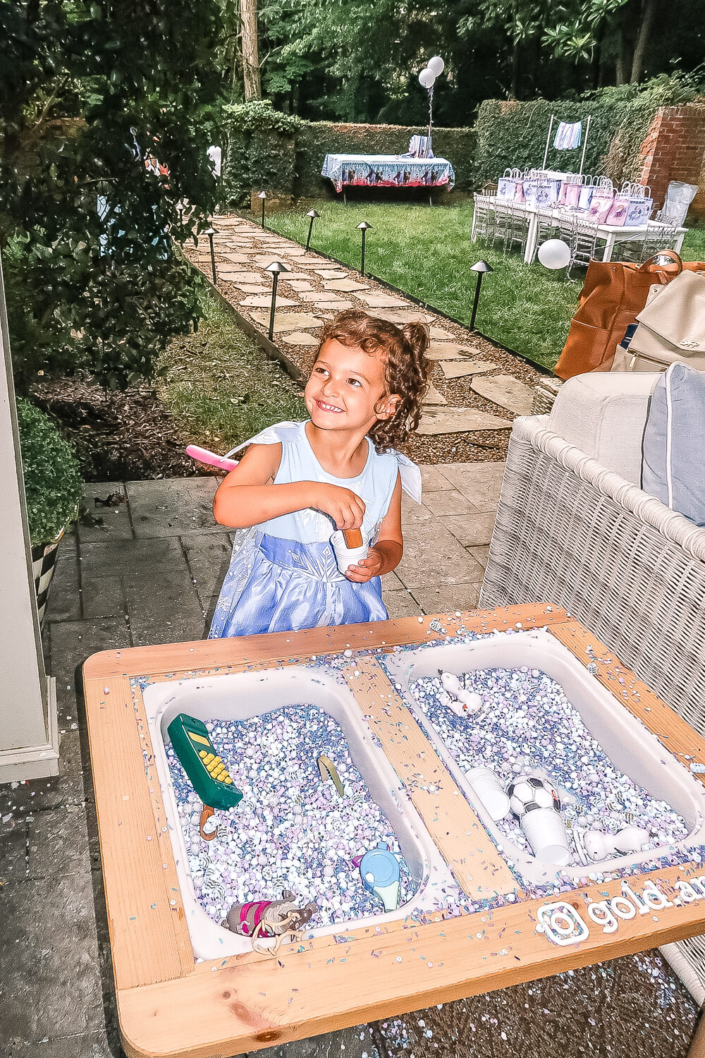 toddler girl smiling standing at sensory table that is frozen themed