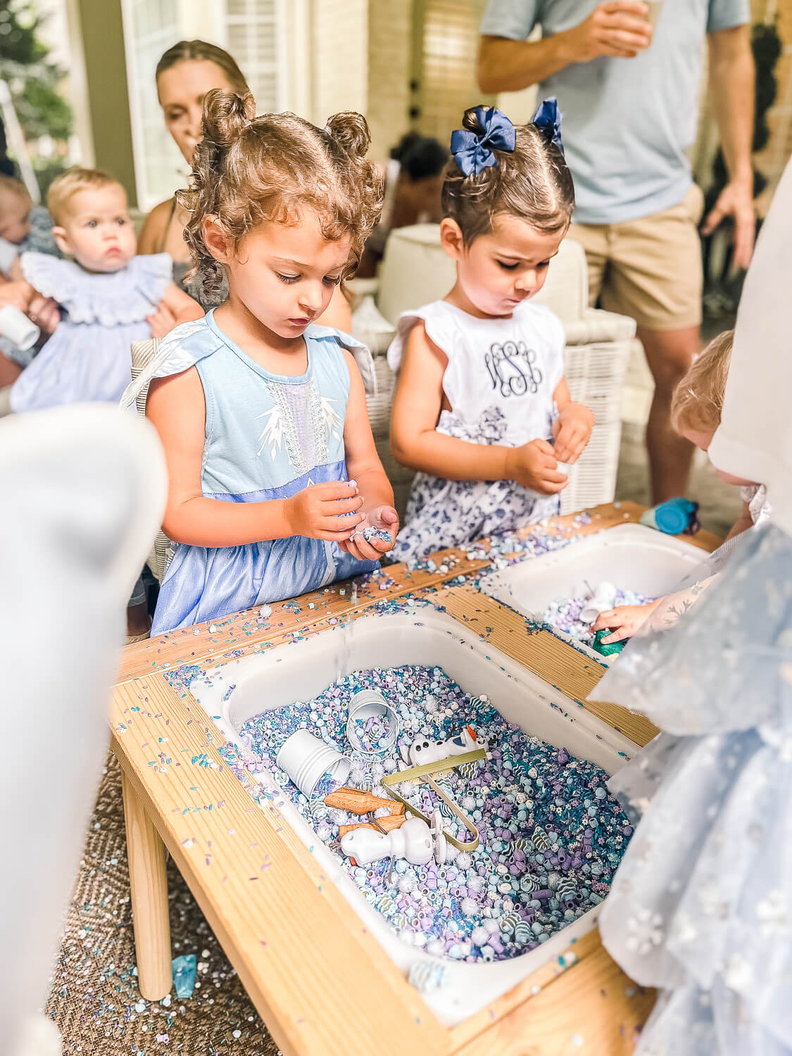 little girl in frozen elsa dress standing at a frozen sensory table