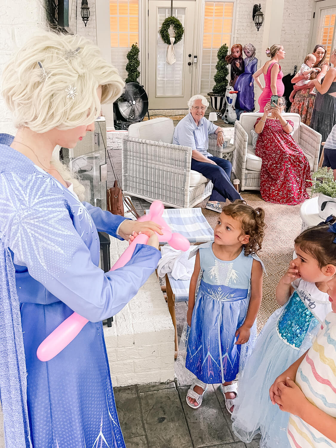 woman dressed like elsa from Frozen making balloon animals for toddler girl