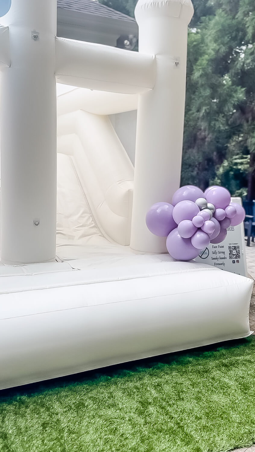 white bouncy castle with balloon arch with blue and purple balloons